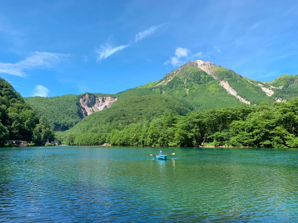 山に囲まれた美しい湖で、一隻のボートが穏やかな水面を進んでいる